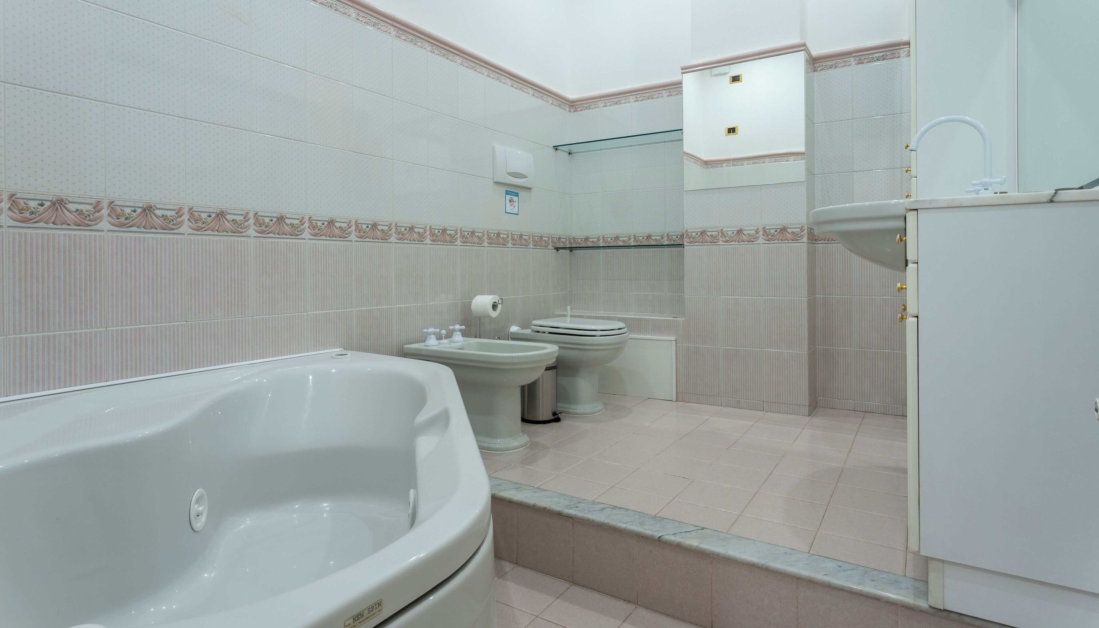 A bathroom with a bathtub, two toilets, and a sink.