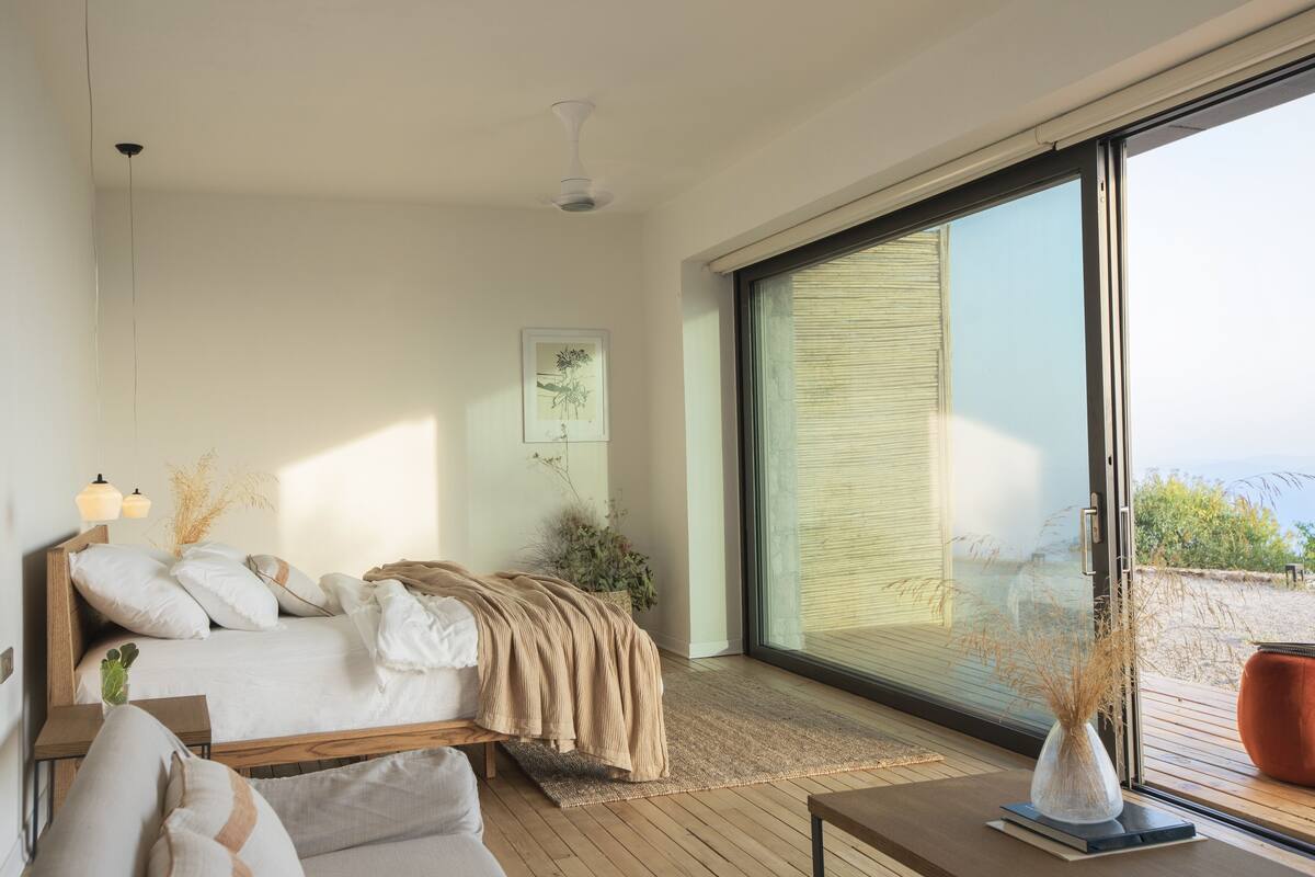 Une chambre moderne avec un lit, une table de chevet et une grande fenêtre donnant sur un beau paysage.