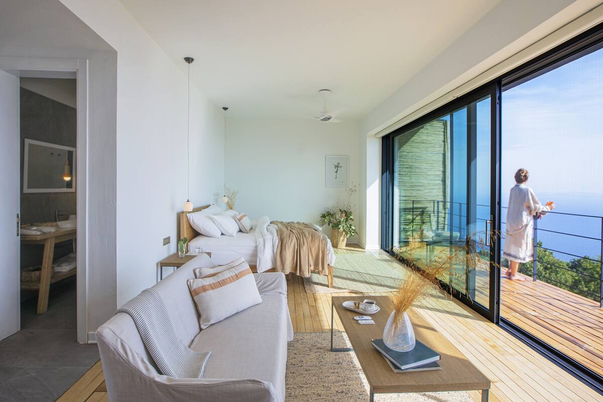 Un intérieur moderne avec un canapé, une table basse et un balcon offrant une vue sur la mer.