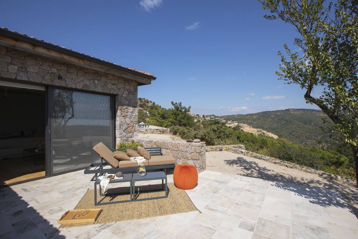 Un espace extérieur aménagé avec un mur en pierre, une table et un fauteuil de détente.