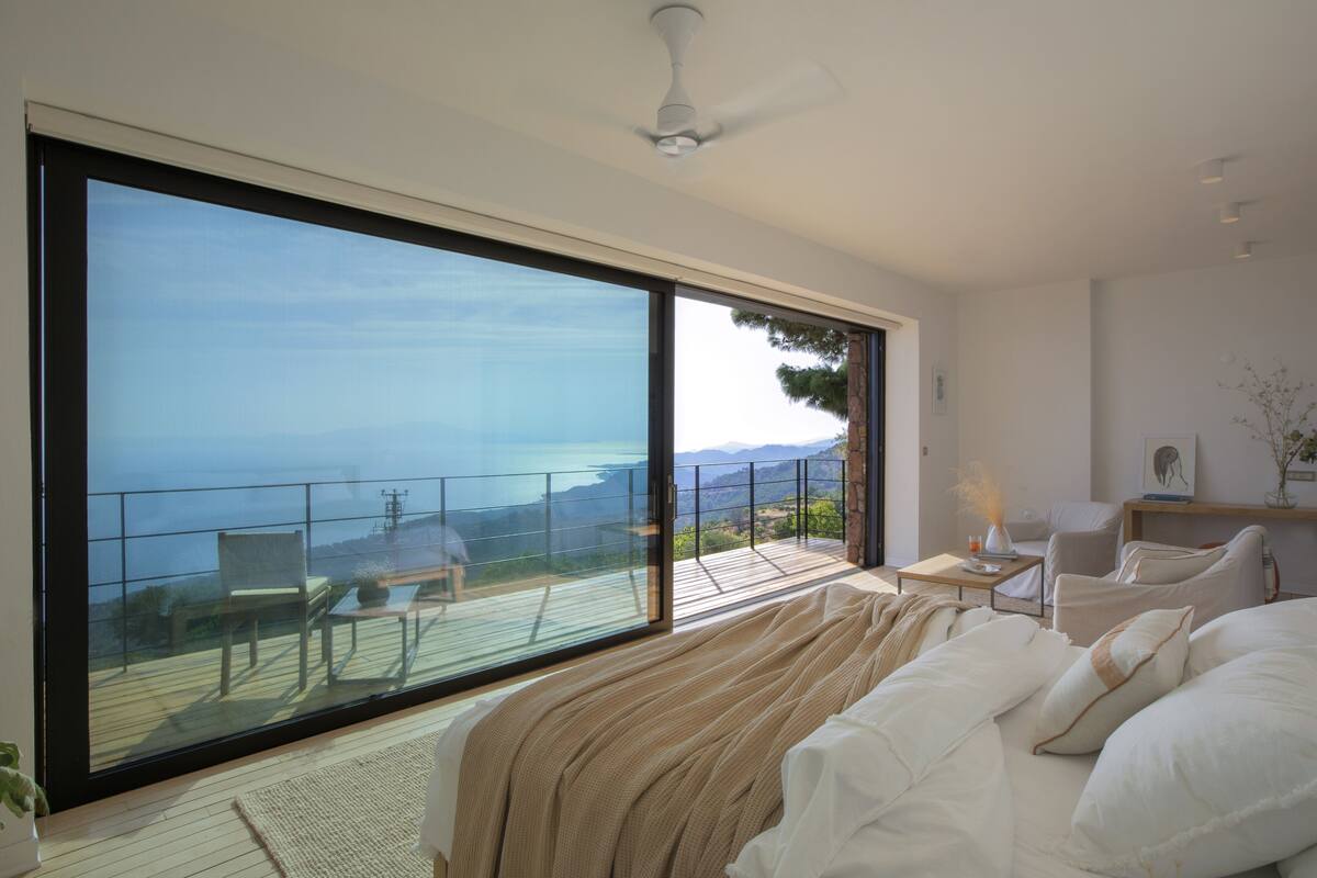 Une chambre dotée d’une grande porte-fenêtre coulissante donnant sur un balcon avec une vue panoramique.