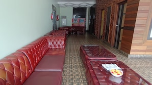 A long red leather bench seating area with a tiled floor and a glass table with a plate of fruit. - N k Grand Days hotel (Port Blair)