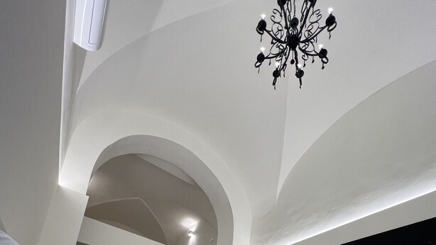 A modern bedroom with a bed, a TV, and a chandelier. - Motta Palace Apartments and Rooms (Motta Sant'Anastasia)
