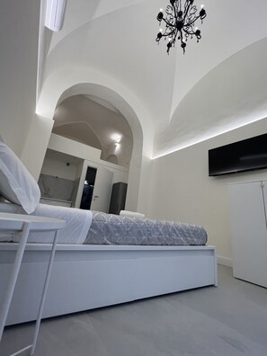 A modern bedroom with a bed, a TV, and a chandelier. - Motta Palace Apartments and Rooms (Motta Sant'Anastasia)