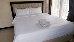 A neatly made bed with white linens and a folded towel on top, in a room with a simple, clean design. - Hotel O Edotel Smkn 5 Palopo Near Bukit punai (Palopo)