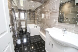 Ein modernes Badezimmer mit Toilette, Badewanne und Waschbecken.