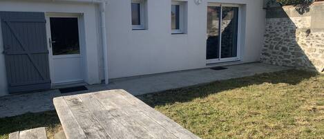 A house with a tiled roof, a garage door, and a small patio area with a wooden table.