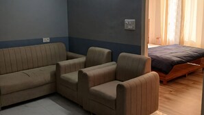 Una sala de estar con un sofá seccional, una cama de madera y un ventilador de techo.