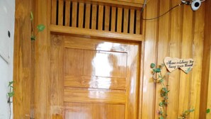 Una puerta de madera con un picaporte de metal, una planta en maceta a la derecha y una pequeña señal encima de la puerta.