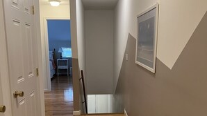 A hallway with wooden flooring, white doors, and a ceiling light.