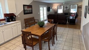 A spacious kitchen with a dining table, chairs, and a coffee maker.