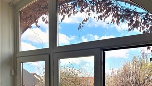 Habitación con un gran ventanal que da a un patio con plantas en macetas y vista al cielo.
