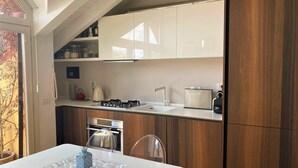 Una cocina moderna con armarios blancos, una estufa a gas, un lavamanos y un refrigerador.