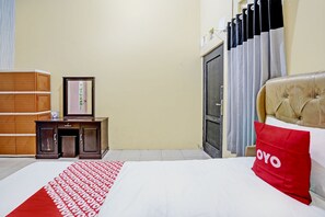 Ein Hotelzimmer mit einem Bett, einem Holzschrank, einem Schreibtisch mit Stuhl und einer Tür mit Vorhängen.