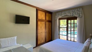 Camera d'albergo con due letti, televisione, finestra con tende e vista sulla piscina.