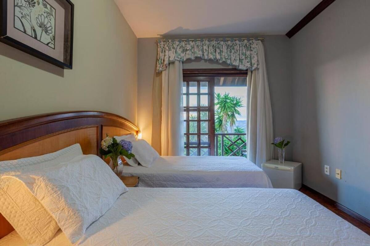 Una habitación de hotel con dos camas, una ventana que da a zonas verdes y un cuadro en la pared.