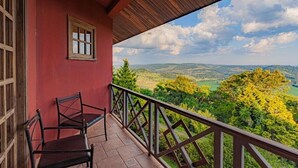 Un balcone con vista su un paesaggio verde e un edificio rosso.