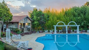 Una piscina con bordo curvo, circondata da posti a sedere all'aperto e un gazebo.