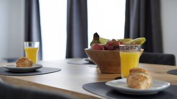 Ein Frühstückstisch mit Croissants, einer Obstschale und Gläsern Orangensaft.