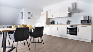 Una cucina moderna con mobili bianchi, forno integrato e microonde.
