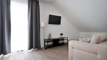 Una sala moderna con un sofá, un televisor montado en la pared, una lámpara y una mesita con objetos decorativos.