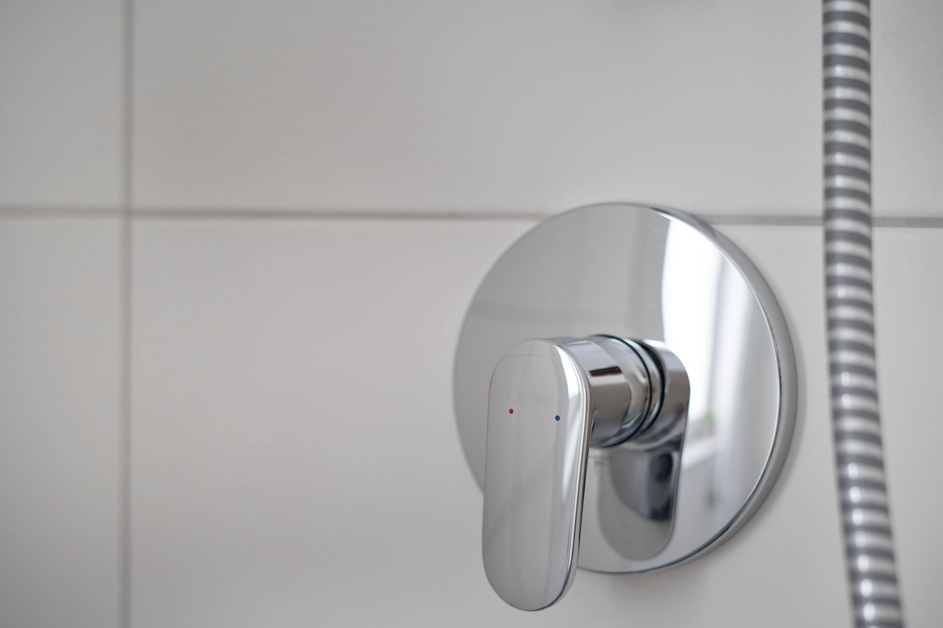 Un baño moderno con grifo cromado y manguera de ducha flexible.