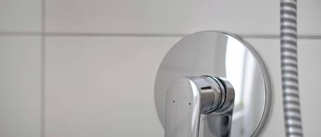 Un baño moderno con grifo cromado y manguera de ducha flexible.