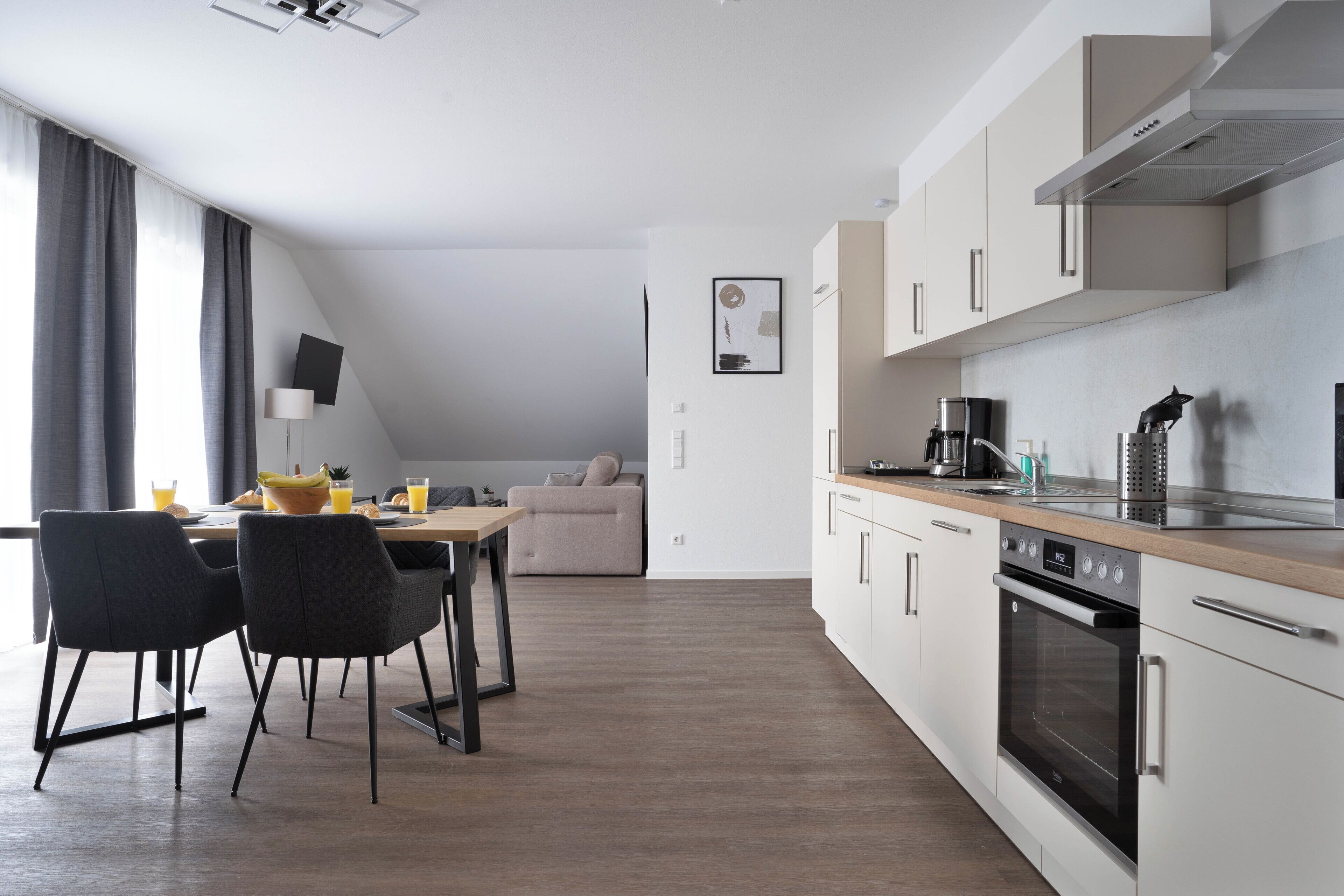 Una cocina moderna con armarios blancos, encimera de madera y horno integrado.