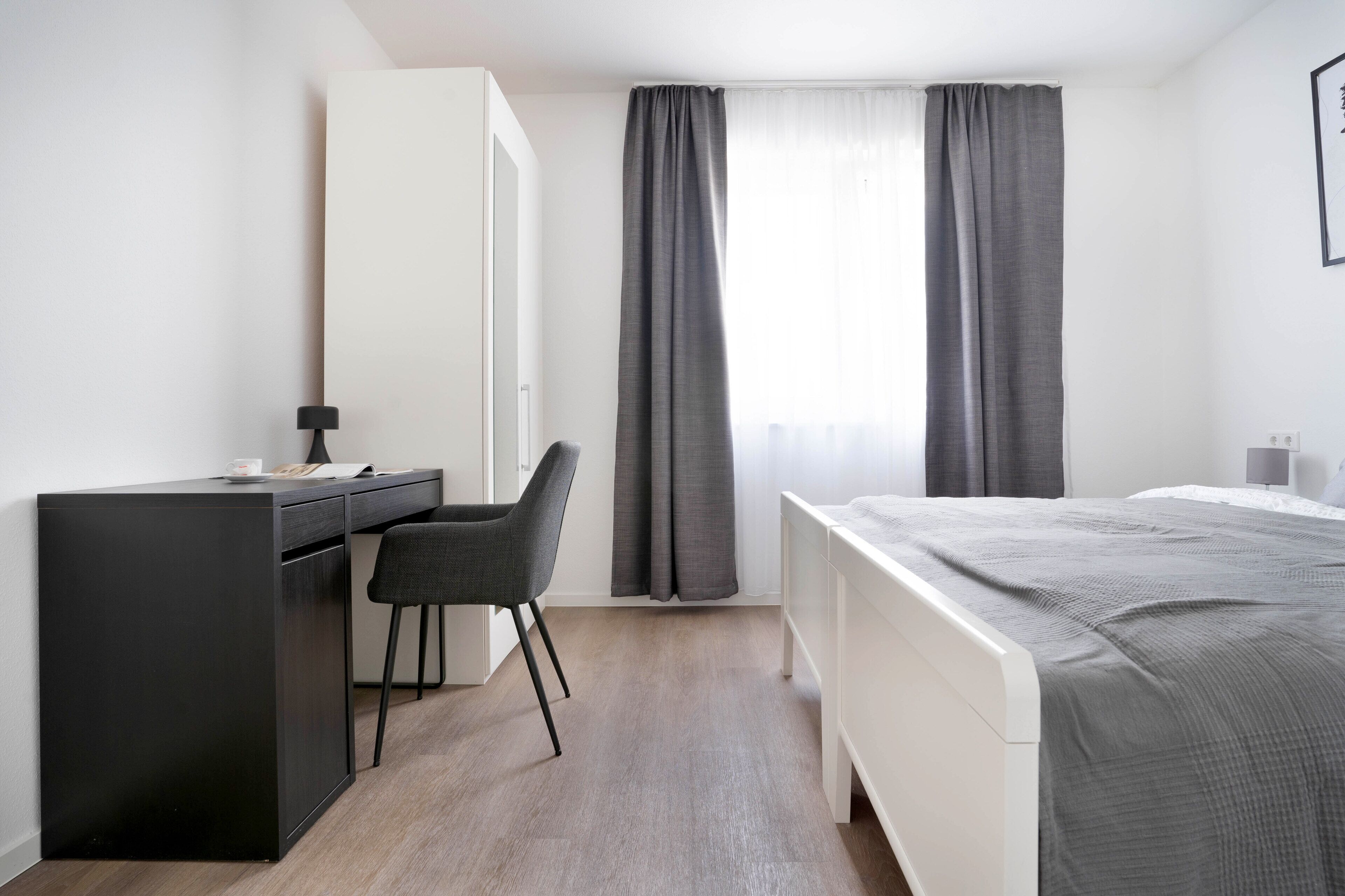 Ein modernes Hotelzimmer mit Schreibtisch, Stuhl und Bett.