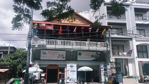 A two-story building with a balcony, flags, and signs indicating it is a guest house. - Sarah Guest House (Siem Reap)