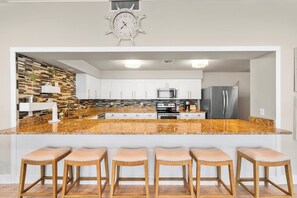 A modern kitchen with a central island, white cabinets, a stainless steel refrigerator, and a clock on the wall. - Oceanfront Condo on traffic free beach - Great views from 403 Lighthouse Shores (Ponce Inlet)