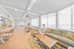 A spacious living area with a wooden floor, a sofa, a coffee table, and a dining table with chairs. - Ocean Breeze 2/2 Oceanfront Traffic Free Beach (Ponce Inlet)
