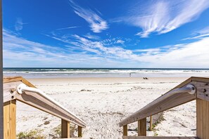A wooden beach chair and a wooden railing overlooking a sandy beach with waves and a clear sky. - Ocean Breeze 2/2 Oceanfront Traffic Free Beach (Ponce Inlet)