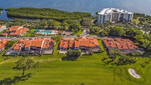 Vista aérea de un complejo turístico costero con varias edificaciones, una piscina y un campo de golf.