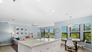 Una cocina moderna con una isla grande, comedor y amplios ventanales con vistas al exterior.
