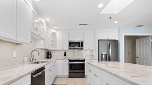 Una cocina moderna con armarios blancos, un refrigerador de acero inoxidable, un microondas y un horno.