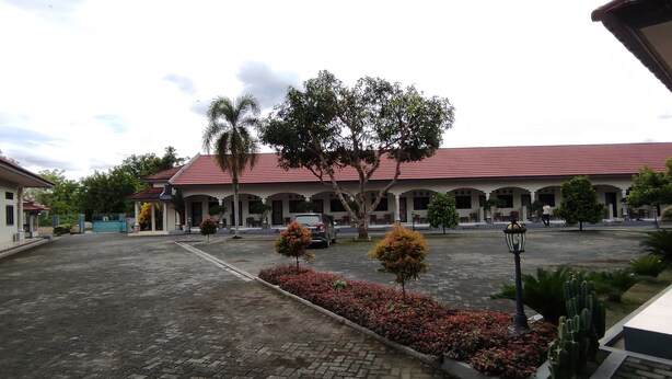 A courtyard with a building featuring a red-tiled roof, surrounded by trees and a paved area. - OYO 93051 Wisma Syariah Buloe Near Lapangan Abubakar Lambogo Batili Enrekang (Enrekang)