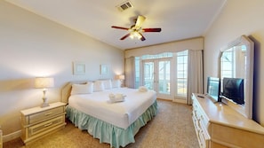 Une chambre d’hôtel avec un grand lit, un ventilateur de plafond, une télévision et une vue par la fenêtre.