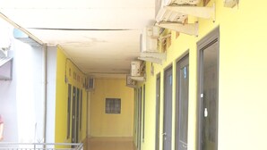 A corridor with tiled flooring, yellow walls, and doors numbered 9 to 11. - OYO 93021 Kost Dison (Bekasi)