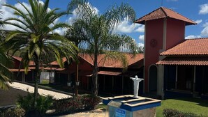 A pool area with a clear blue pool, palm trees, and a building with a red roof. - Pousada Apear (Andradas)