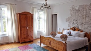 Een slaapkamer met een houten bed, een grote kast, een kaart aan de muur en een kleurrijk vloerkleed.