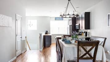 A modern kitchen with dark cabinets, a chandelier, and a dining area with a table set for four.