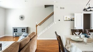 A dining area with a table set for two, a staircase leading to another room, and a blue cabinet against the wall.