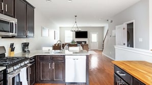 A modern kitchen with dark wood cabinets, a built-in microwave, a stove, and a dishwasher.