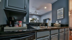 Una cocina moderna con armarios grises, encimera negra y pileta de acero inoxidable.