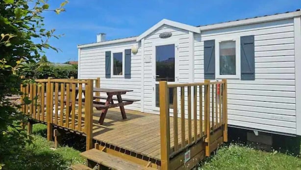 A mobile home with a wooden deck and picnic table. - Modern Mobilome (Petit-Caux)