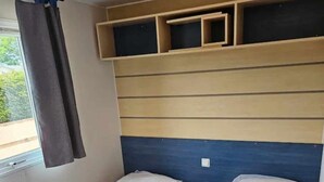 A small, compact room with two single beds, wooden headboards, and built-in shelves above the beds. - Modern Mobilome (Petit-Caux)