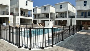 A residential building with a swimming pool, enclosed by a black fence.
