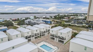 A coastal residential area with multiple two-story houses, a swimming pool, and a view of the ocean.