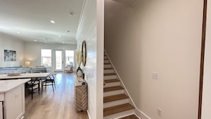 A spacious kitchen with a dining area, a staircase, and a living room with a sofa and a lamp.